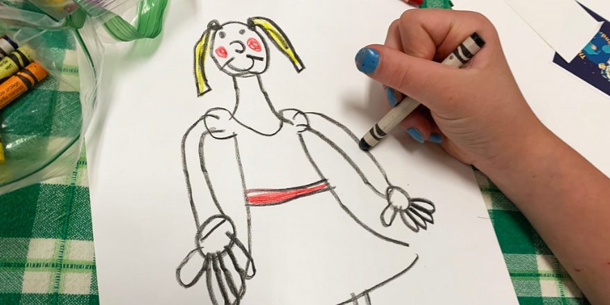 A child drawing with crayons on paper.